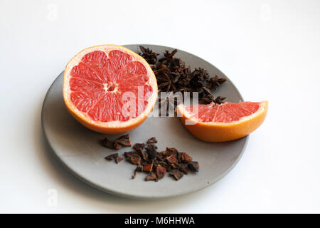 Juicy sliced grapefruit and heap of star anise species isolated on grey concrete plate Stock Photo