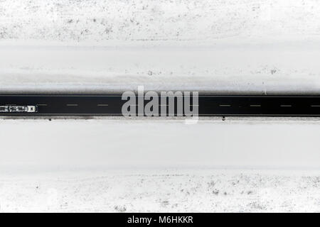 Aerial view of winter road in snowy fields. Drone captured shot from above. Stock Photo