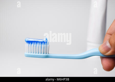a blue toothbrush in the hand with white toothpaste Stock Photo - Alamy