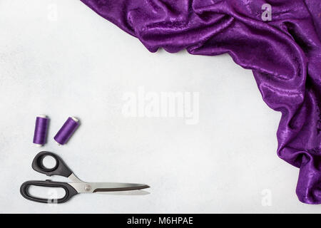 violet cloth, scissors, thread on a light background. view from above.  copy space Stock Photo