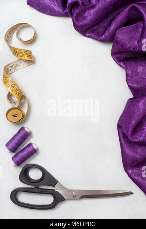 violet cloth, scissors, thread on a light background. view from above.  copy space Stock Photo