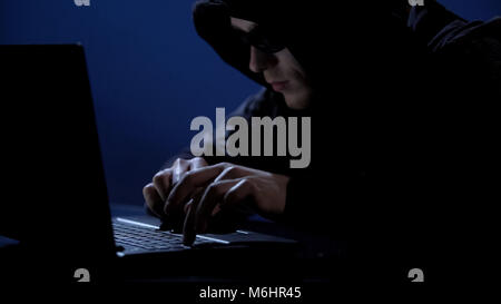 Criminal secretly using laptop, unauthorized access to confidential information Stock Photo