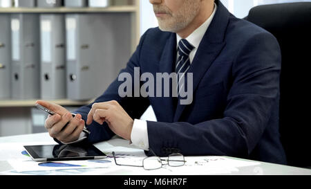 Man in business suit checking email on smartphone in office, modern technology Stock Photo