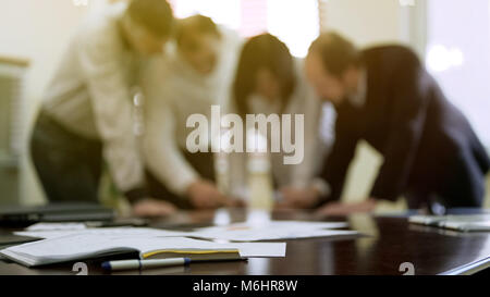 Company colleagues discussing report papers at business meeting, cooperation Stock Photo