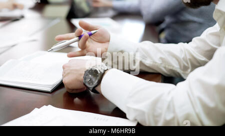 Bored employee sitting at business conference and spinning pen in his hand Stock Photo