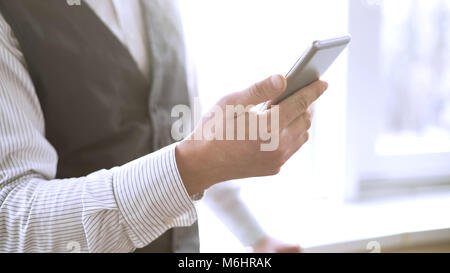 Successful businessman dialing number on mobile phone, calling company partner Stock Photo