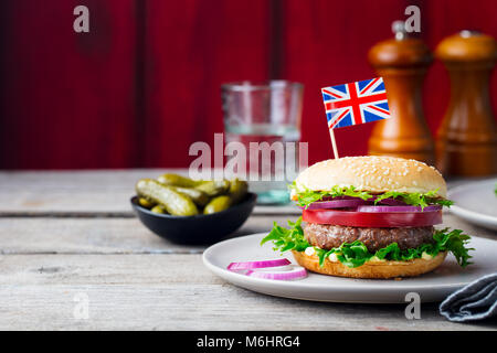 Burger with British flag on top. Wooden background. Copy space. Stock Photo