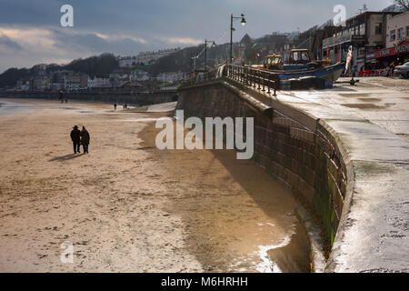 Filey Yorkshire beach, near the boat-ramp known as Coble Landing in Filey, Yorkshire, a middlle aged couple walk on the beach in winter, England, UK Stock Photo