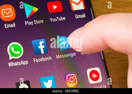 Closeup of the Facebook Messenger app on a smartphone being selected by a woman's finger pointing at the app on the cell phone screen Stock Photo