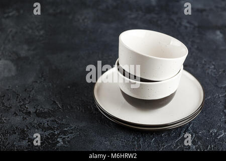 New Ceramic Bowls and Plates in a pile on a black background Stock Photo