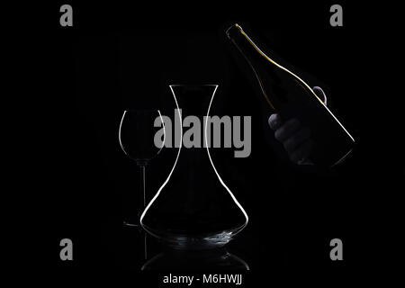 Hand in white glove holds bottle of wine and decanter Stock Photo