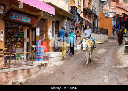 Woman riding horse and hikers in the small village of Imlil - the base camp for hikers climbing Jebel Toubkal in the Atlas Mountains, Morocco Stock Photo