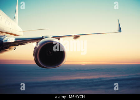 Aircraft flight over the clouds during sunrise Stock Photo