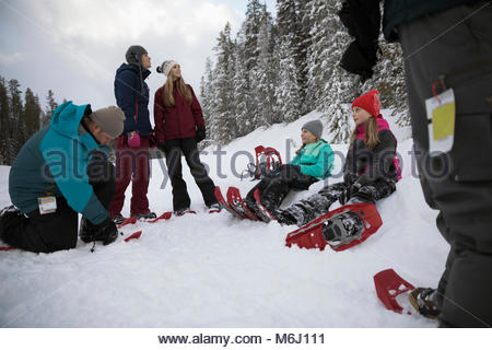 Family preparing for snowshoeing, putting on snowshoes in snow