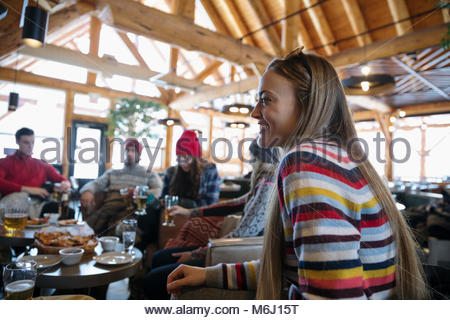 Smiling young woman enjoying apres-ski with friends in ski resort lodge