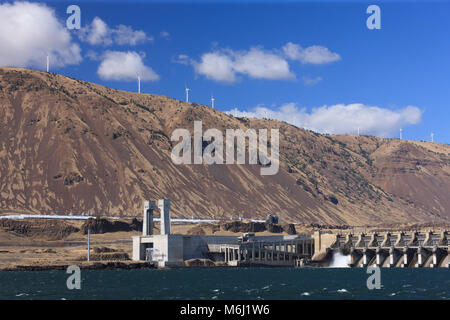 Multiple commercial windmills high above large hydroelectric dam on Columbia River depicting modern green energy resources of wind and water power USA Stock Photo