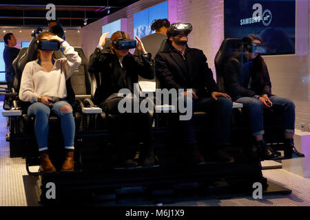 People wearing virtual reality goggles at a technology store; the vr headsets turn movie watching into a personal immersive experience. Stock Photo