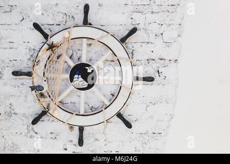 Old Ship Wheel (helm) on brick wall for decoration Stock Photo