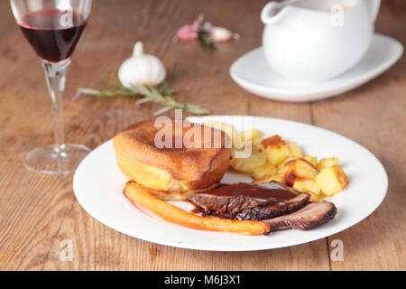 Roast beef with Yorkshire pudding, gravy, wine, roasted carrot and rosemary and garlic potatoes Stock Photo