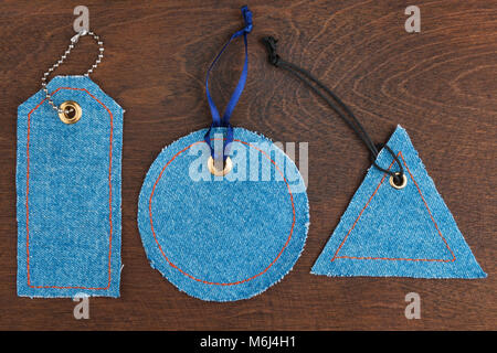 Set, collection of price tags made of denim lying on a dark wood. View from above. Ideas and concepts of fashion. Stock Photo