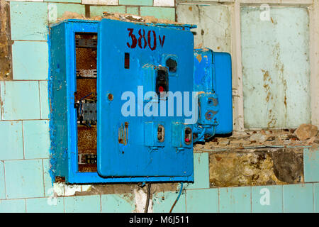 Old dismantled and rusty electrical panel assembly on an abandoned and destroyed factory against a backdrop of chaos. Destruction and vandalism. Ukrai Stock Photo