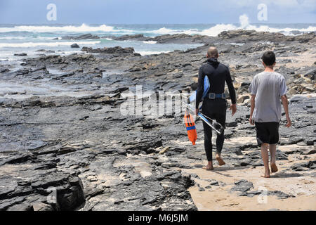 A spear fisher with his equipment walking near the shoreline in Coffee Bay at the Indian Ocean in the Eastern Cape at the Wild Coast of South Africa Stock Photo