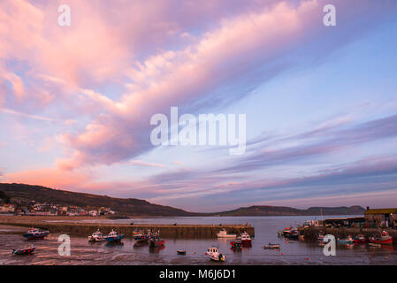 Vibrant auturmn colours in the sky over Lyme Regis at sunset. Stock Photo