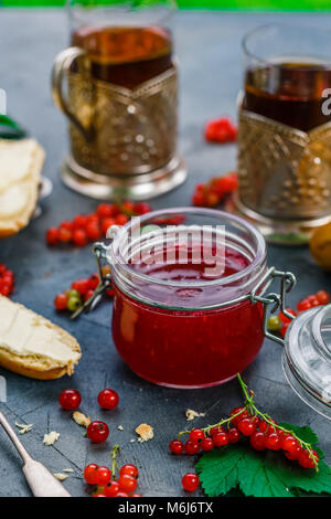 Red currants and jar of jam in garden Stock Photo