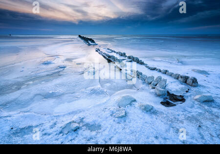 frozen breakwater in ice on Ijsselmeer lake, Netherlands Stock Photo