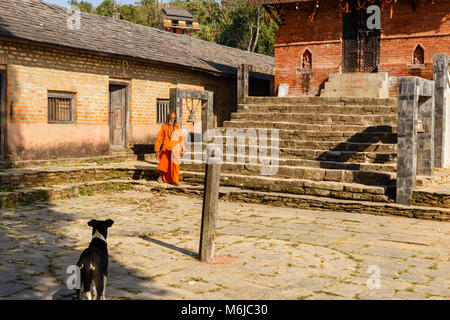 Nepali aged pilgrim in orange robe in the temple Stock Photo