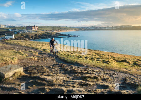 A mountain biker riding up a trail on Towan Head in Newquay Cornwall. Stock Photo