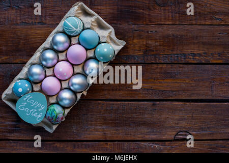 Background image of pastel painted Easter eggs in tray on rough wooden table with intentional copy space Stock Photo