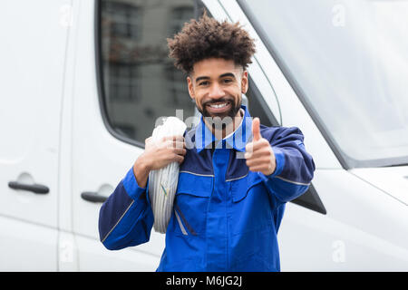 Portrait Of Smiling Electrician With White Cable Coil Standing By Van Stock Photo