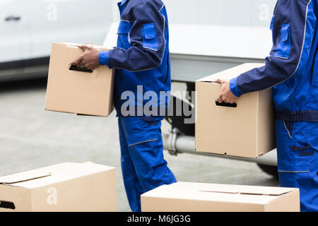 Close-up Of Two Delivery Men Holding The Cardboard Boxes Stock Photo