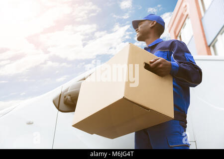 Low Angle View Of Loader Man Standing Near The Van Holding Cardboard Box Stock Photo