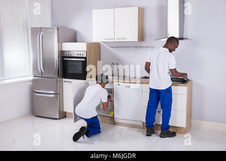 Rear View Of Two Young Service Men In Uniform Assembling Kitchen Stock Photo