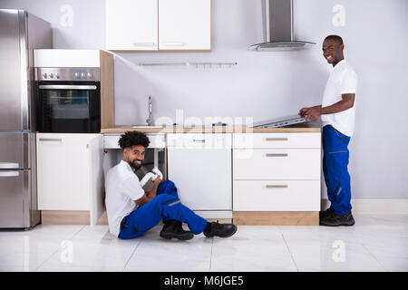 Rear View Of Two Young Service Men In Uniform Assembling Kitchen Stock Photo