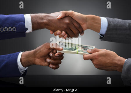 Cropped Image Of Businessman Shaking Hands While Bribing Partner Outdoors Against Gray Background Stock Photo