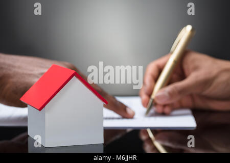 Businessman Signs Contract Behind Home Architectural Model Stock Photo