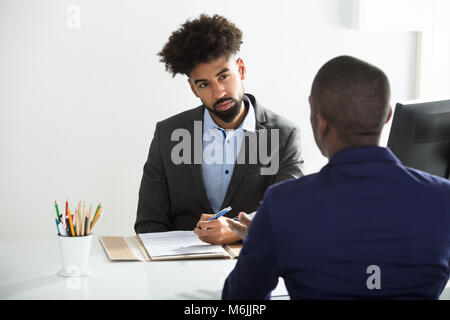 Young Businessman Interviewing Male Candidate In Office Stock Photo