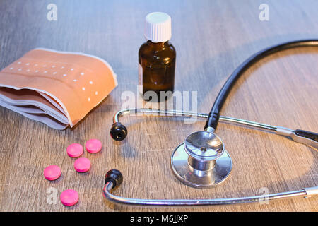 Stethoscope, pill and bandage on wooden background, medical concept Stock Photo