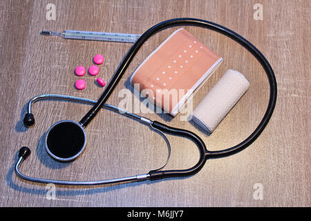 Stethoscope, pill, thermometer and bandage on wood background, medical concept Stock Photo