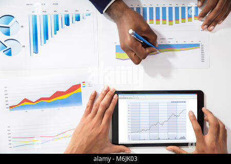 High Angle View Of Two Businesspeople Analyzing Graph By Using Digital Tablet Stock Photo
