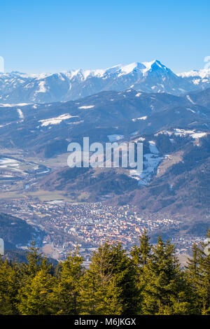 Aerial view from mountain Rennfeld to valley Muerztal with town Bruck an der Mur and distant snowy mountain top Goesseck in Winter Stock Photo