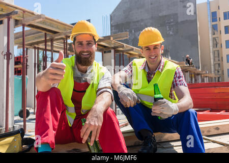 Two young workers drinking a cold beer during break at work Stock Photo
