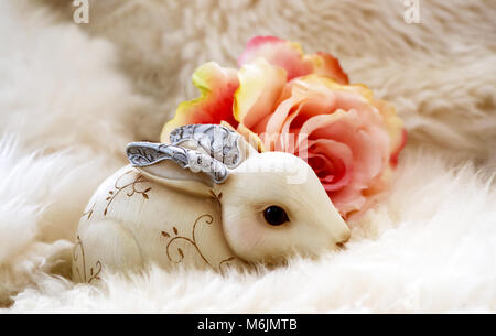 Ornate Christmas Bunny with silver metal ears peeking out of white fur with soft peach rose Stock Photo