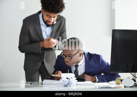 Worried Man Looking At Young Auditor Analyzing Bill At Workplace Stock Photo