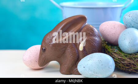 Australian milk chocolate Bilby Easter egg with eggs in nest against a blue and white background with copy space. Stock Photo