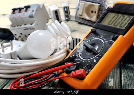 Close-up of a tester and other components for residential electrical installation on rustic wooden table Stock Photo