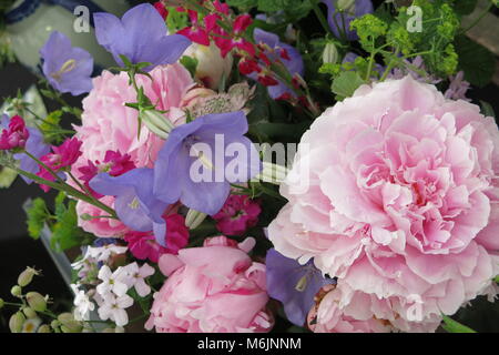 A feminine and romantic flower display of pink peonies and blue bell-shaped flowers